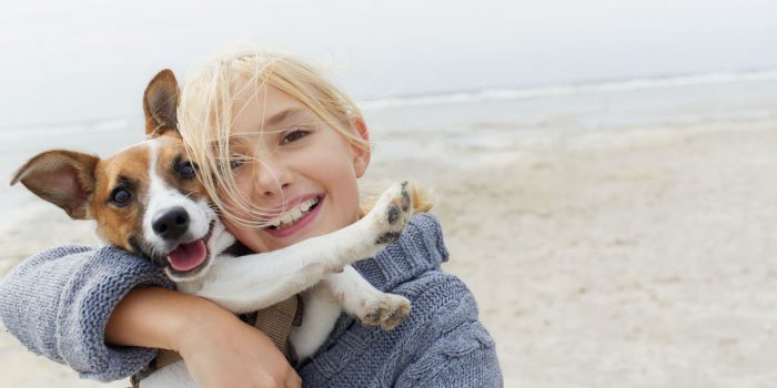 ילדה מחזיקה כלב בזרועותיה