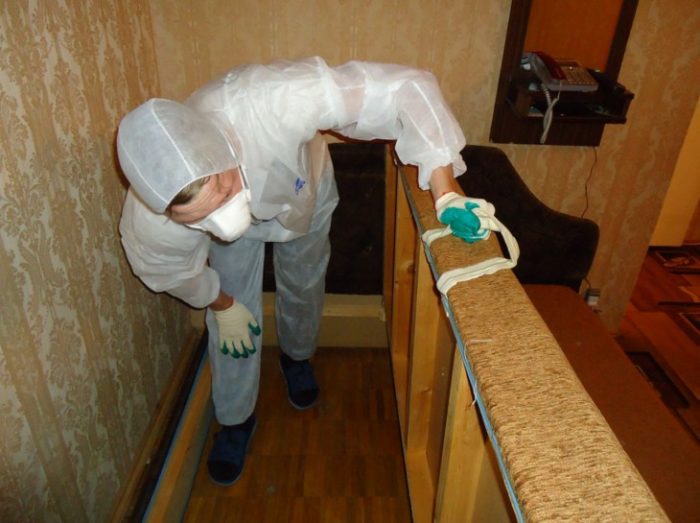 גבר בחליפת מגן מטפל ברהיטים נגד פשפשים.